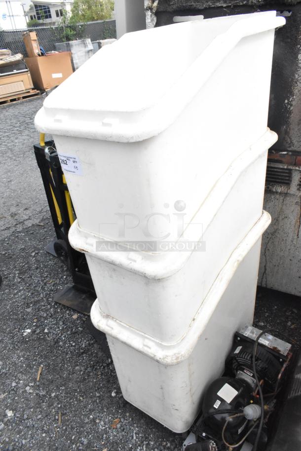 3 stacked white poly ingredient bins on commercial casters, visible wear, outdoor setting.