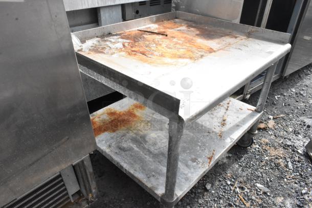 Stainless steel equipment stand with rust, metal under shelf, commercial casters, and visible wear. Suitable for industrial use.