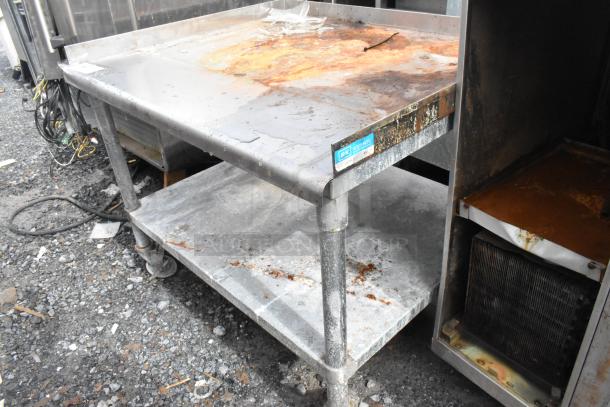 Stainless steel equipment stand with metal under shelf, visible rust and wear, on commercial casters, EK Resources label.