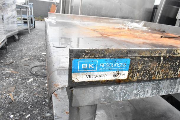 Stainless steel equipment stand by BK Resources, model VETS-3630, with metal under shelf and commercial casters. Visible rust and wear.