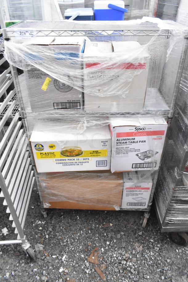 Chrome finish wire shelving unit on commercial casters, filled with boxed contents, wrapped in plastic. Buyer must dismantle.