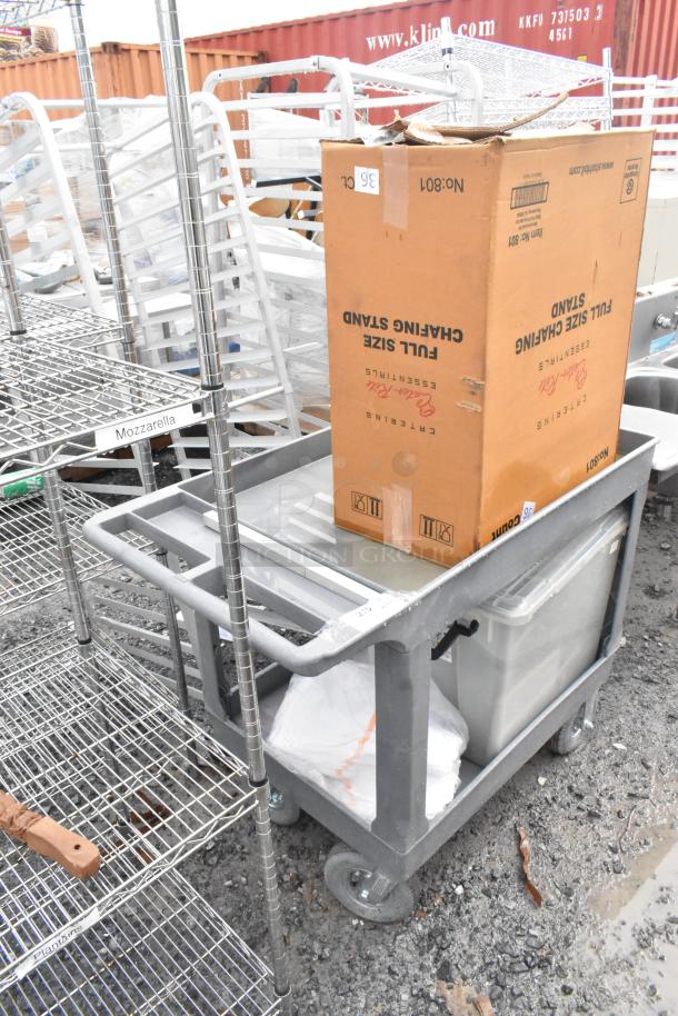 Gray poly 2-tier cart on commercial casters, sturdy condition, suitable for industrial use, box on top for size reference.