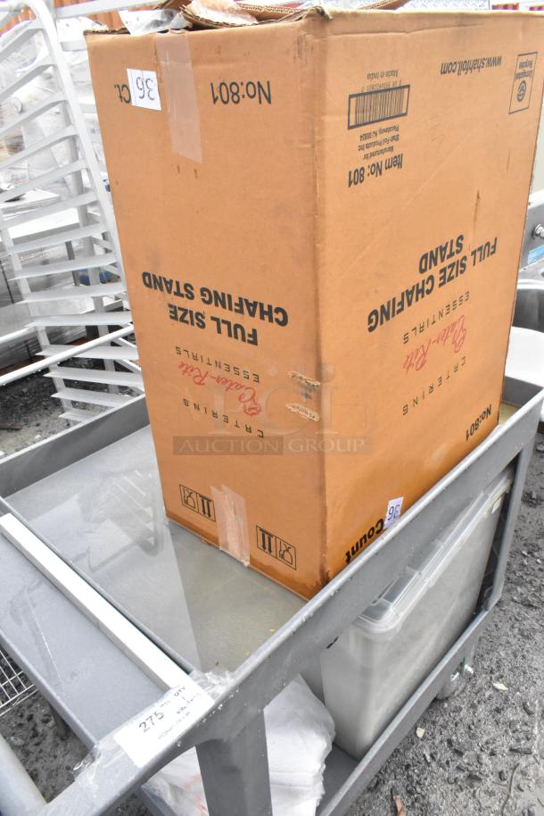 Gray Poly 2 Tier Cart on commercial casters, carrying a cardboard box and a clear plastic container. Appears in used condition.