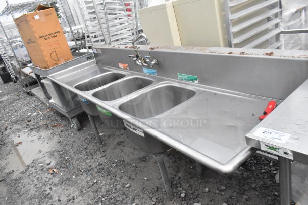 Stainless steel 3 bay sink with dual drain boards, faucet, and handles. Features labels and signs of outdoor use.
