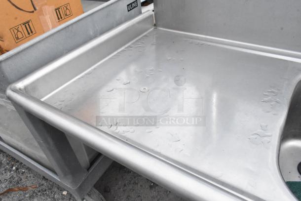 Stainless steel 3 bay sink with dual drain boards, faucet, and handles. Uline branding visible. In good condition.