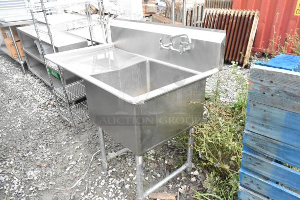 Stainless steel single bay sink with left side drain board, faucet, and handles; sturdy legs, good condition.