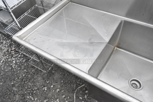 Stainless steel single bay sink with left side drain board, faucet, and handles; lightly used, minor wear visible.