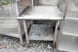 Stainless steel equipment stand with metal undershelf, worn condition, visible rust and wear marks, industrial use.