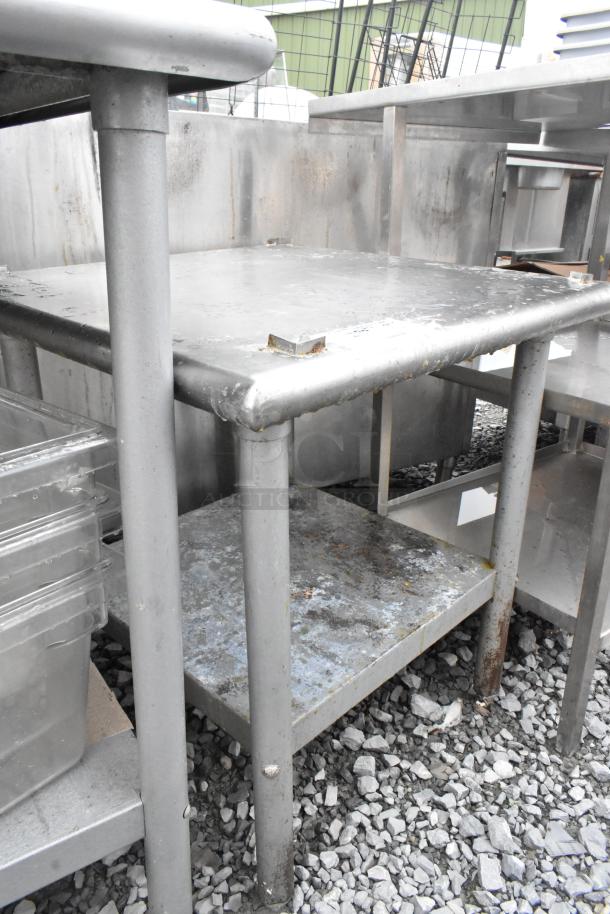 Stainless steel equipment stand with metal under shelf, showing signs of wear. Ideal for industrial kitchens or workshops.