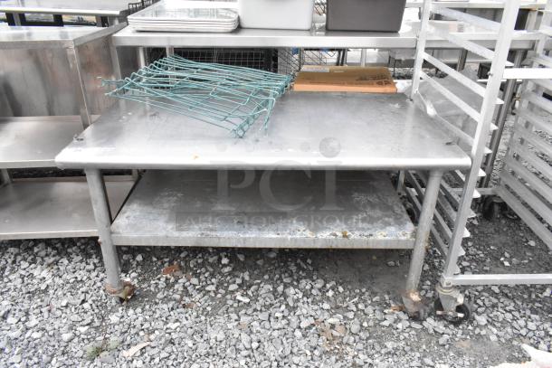 Stainless steel equipment stand with metal under shelf, on commercial casters. Some surface scratches and signs of wear.