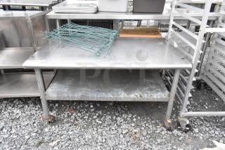 Stainless steel equipment stand with metal under shelf, on commercial casters. Some surface scratches and signs of wear.