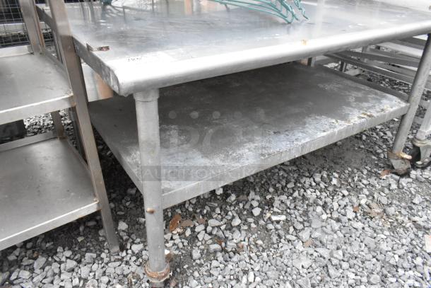 Stainless steel equipment stand with metal under shelf, on commercial casters. Shows signs of use on surface.