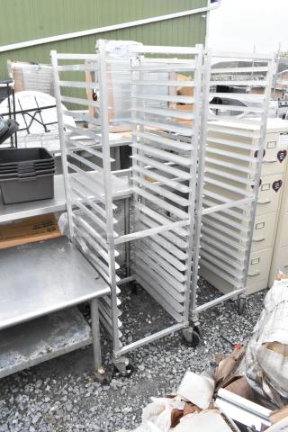 2 metal pan transport racks with commercial casters, in good condition, ideal for kitchen or bakery use.