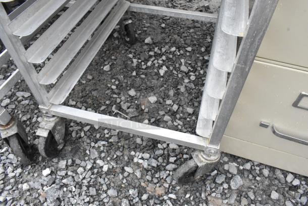 2 metal pan transport racks with multiple shelves on commercial casters, sturdy, suitable for kitchen or bakery use.