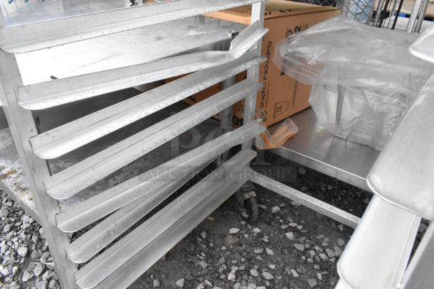 Two metal pan transport racks on commercial casters, featuring multiple slotted shelves, in good condition.