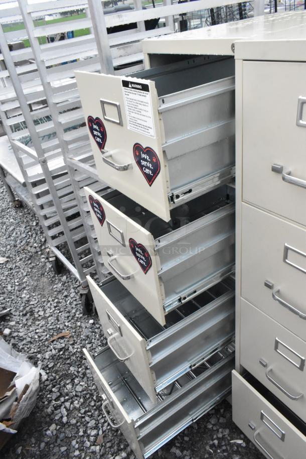 Two beige metal 4-drawer filing cabinets, open drawers, heart decals with "love, serve, care." Good condition, sturdy handles.