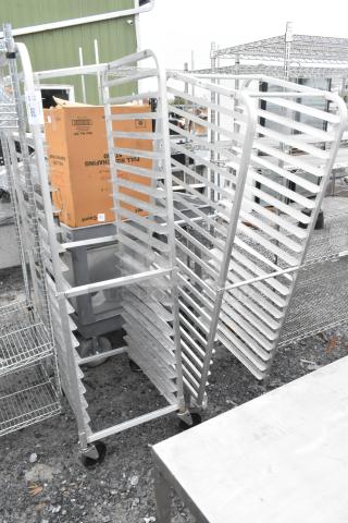 2 metal pan transport racks on commercial casters, featuring multiple shelves for storage, in used condition.