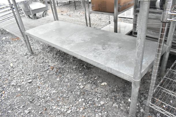 Stainless steel table with metal under shelf, showing slight wear. Ideal for heavy-duty use in commercial settings.