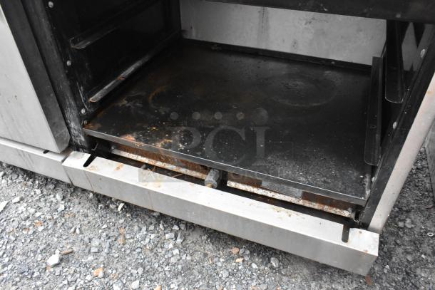American Range stainless steel gas-powered 6-burner range with flat top griddle, two ovens, over shelf, and backsplash. Worn interior.