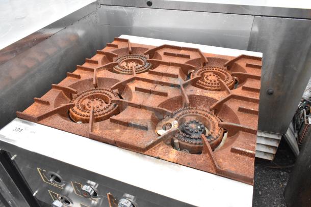 Stainless steel commercial gas-powered 4 burner range on stand, visible rust on burners, knobs intact, tag labeled "301".