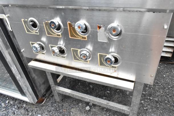 Stainless steel commercial gas range with 4 burners on a sturdy equipment stand, featuring control knobs and visible wear.