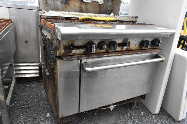 Stainless steel commercial 6-burner gas range with salamander cheese melter, back splash, oven; visible wear and rust.