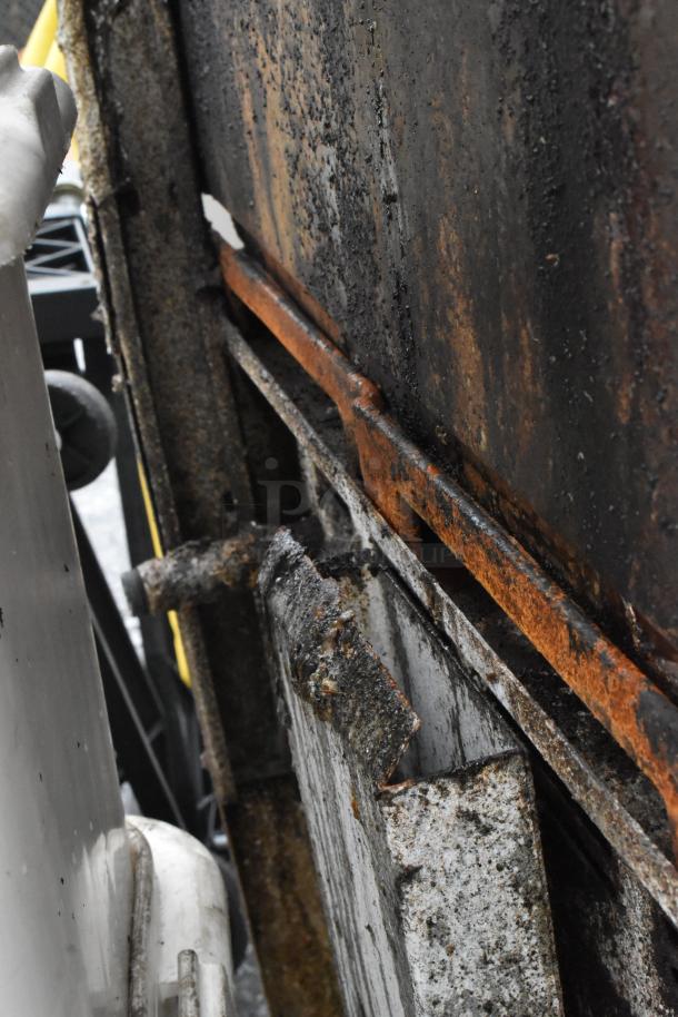 A rusted, worn section of a stainless steel commercial range, showing signs of heavy use and deterioration.