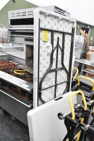 Two folding tables, white plastic, metal legs, stackable. "Lifetime" label visible. Good condition, suitable for events.