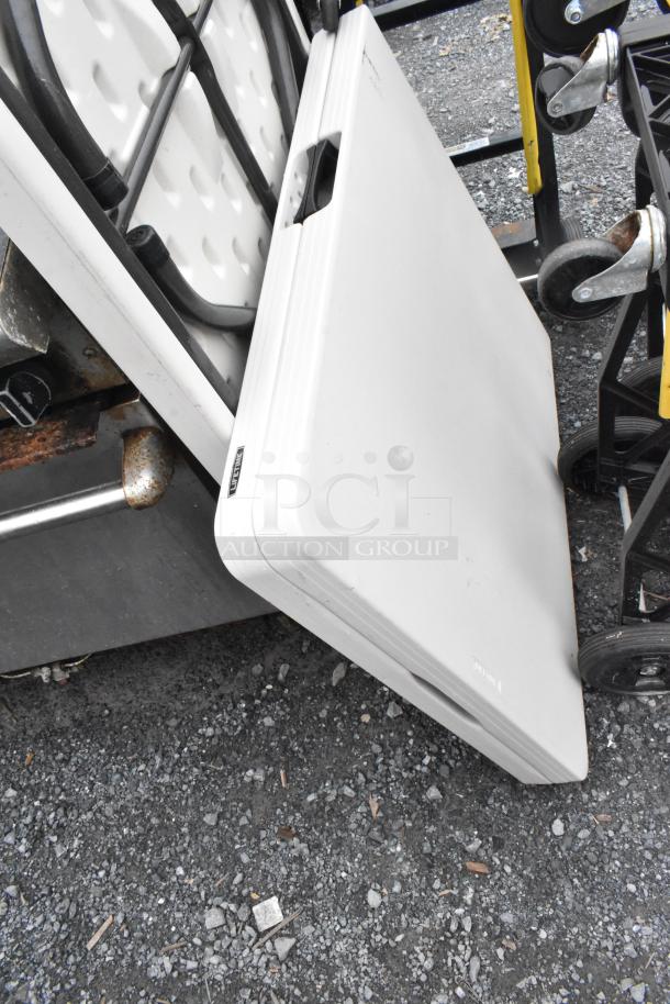 Two white folding tables with sturdy legs, compactly folded. Slight wear. Perfect for events or extra workspace.