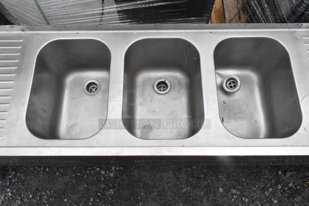 Stainless steel 3-bay back bar sink with dual drain boards. Features integrated drains, showing moderate wear.