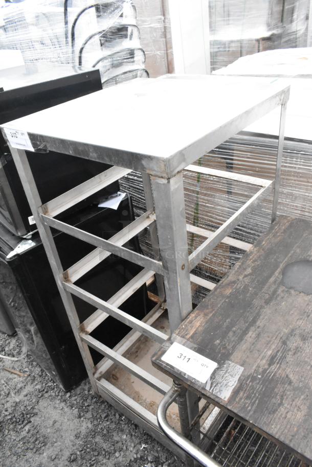 Metal rack on commercial casters, used condition, with multiple shelves and visible signs of wear; auction tag number 311 attached.