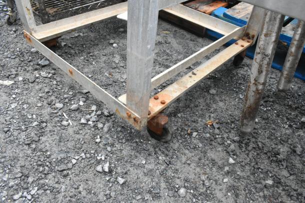 Metal commercial pan transport rack with visible rust, on casters for mobility, suitable for industrial use.