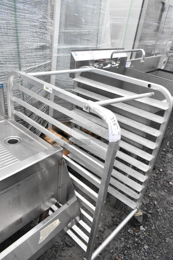Metal commercial pan transport rack on casters, gray finish, multiple shelves, numbered tag visible, used condition.