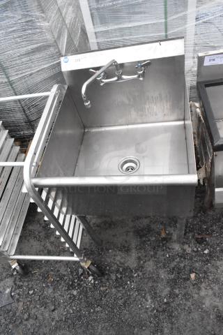 Stainless steel single bay sink with faucet and handles, showing slight wear, NSF certified label visible.