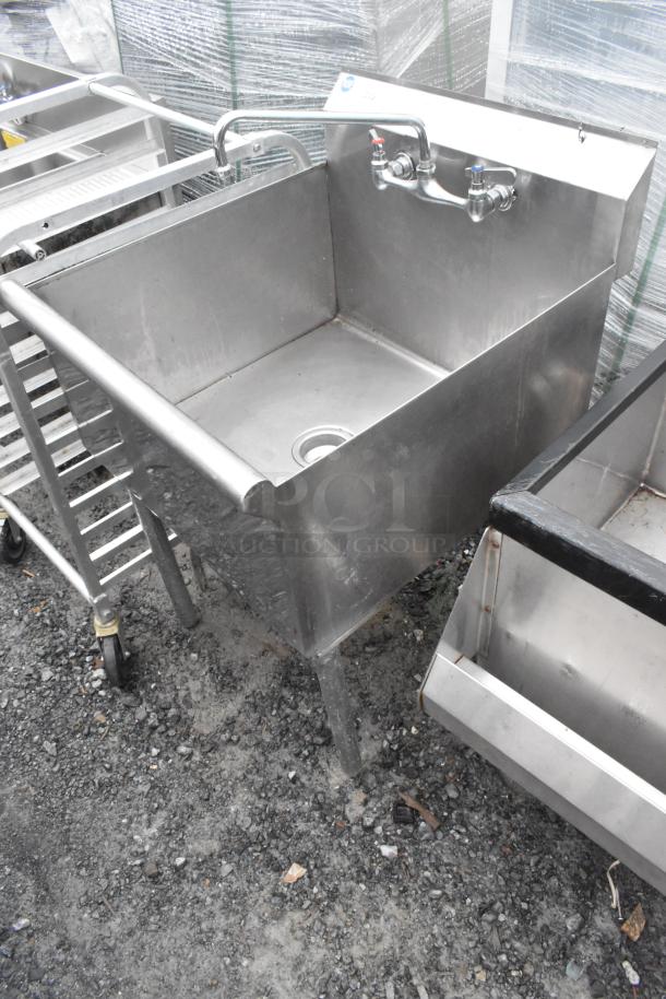 Stainless steel single bay sink with faucet and handles, in used condition. Features sturdy legs and a drain.
