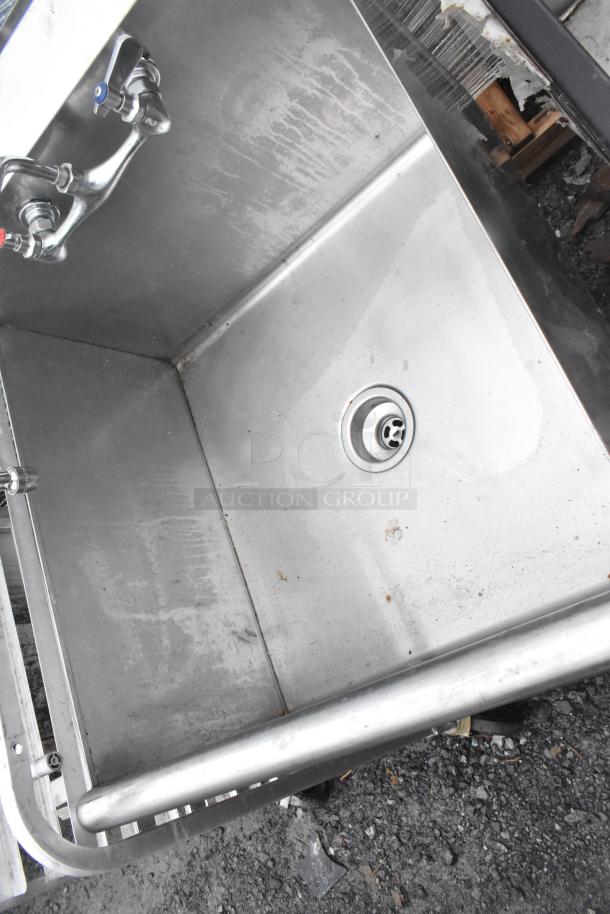 Stainless steel single bay sink with faucet and handles, showing slight wear, suitable for commercial use.