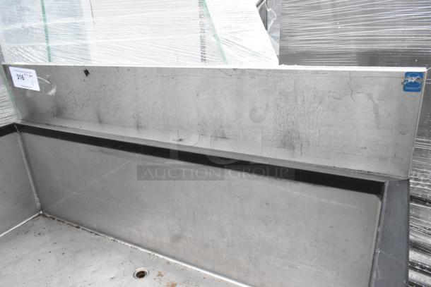 Stainless steel ice bin with speedwell, no legs, showing surface scratches and a drain hole. Inventory tag visible.