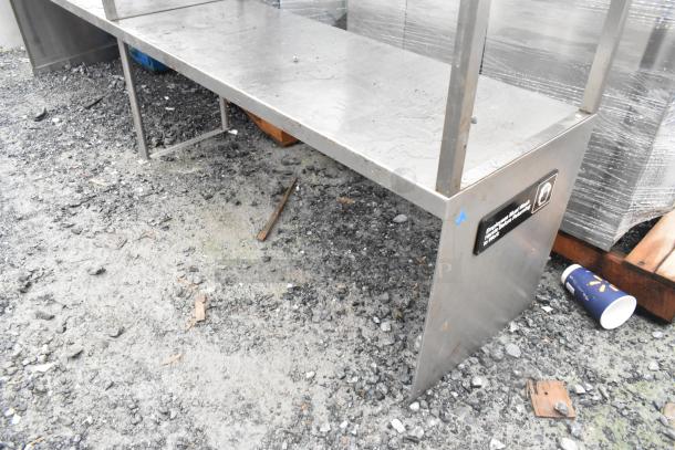 Stainless steel 2-tier overshelf, durable construction, minor surface wear, attached label with safety instructions.