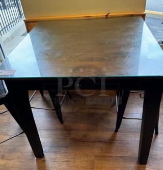 Dining table with glass top, dark wood finish, 40x40 inches, reflective surface, sturdy legs, indoor use.