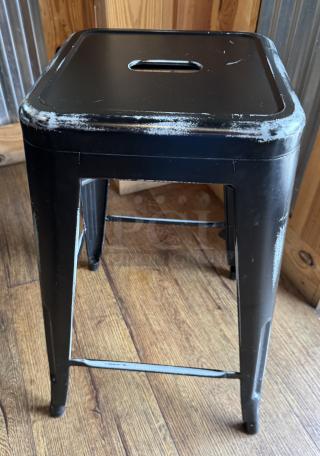 Black metal stool with distressed edges, square seat with handle cutout, sturdy legs; auction set of four.