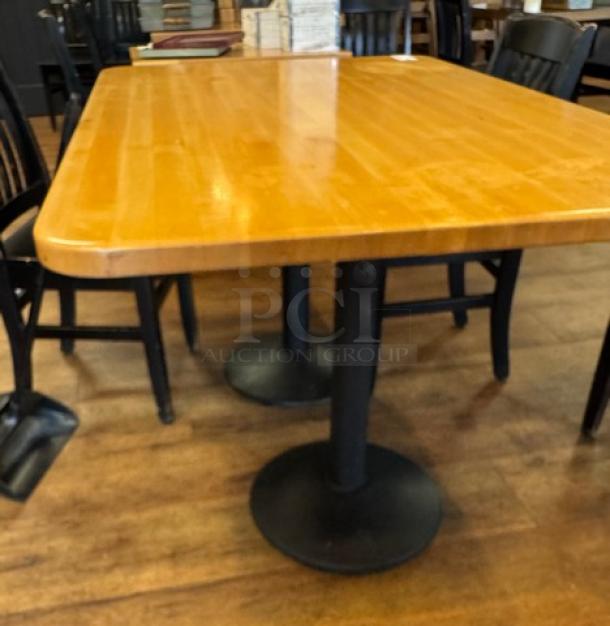 Rectangular wooden dining table with polished surface, supported by two black pedestal legs. Good condition.