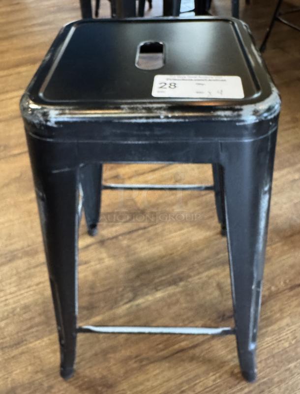 Black metal stool with square seat, visible wear on edges. Auction tag reads "28." Set of 4 stools available.