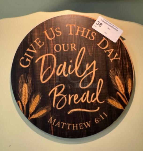 Round wooden sign with "Give Us This Day Our Daily Bread, Matthew 6:11" and wheat design. Auction tag with number 38.