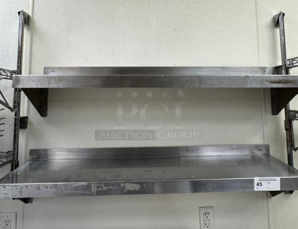 Stainless steel shelving, two-tier, mounted on a wall. Slight wear, auction lot number 45 visible. Perfect for kitchens or storage.