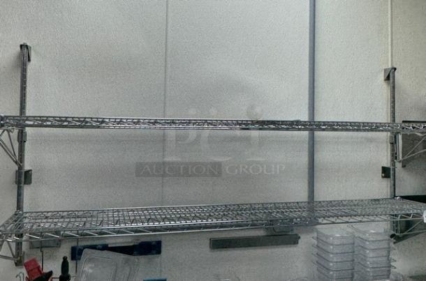 Two-tier stainless wire shelving unit, wall-mounted, used condition, adjustable brackets, durable construction. Ideal for storage.