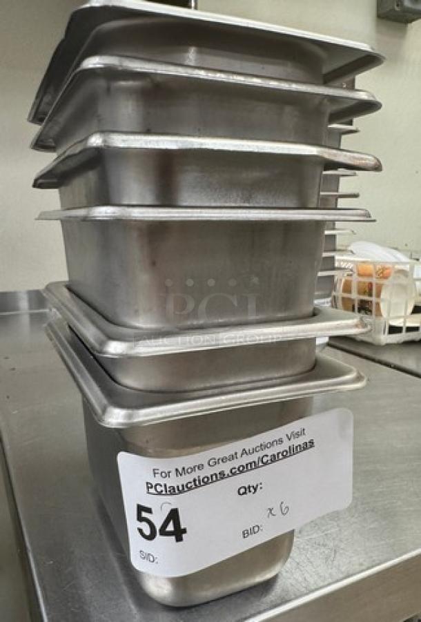 Stack of six 1/6 x 4 stainless steel pans with lids, labeled "Qty: 6," in good condition. Auction sticker visible.