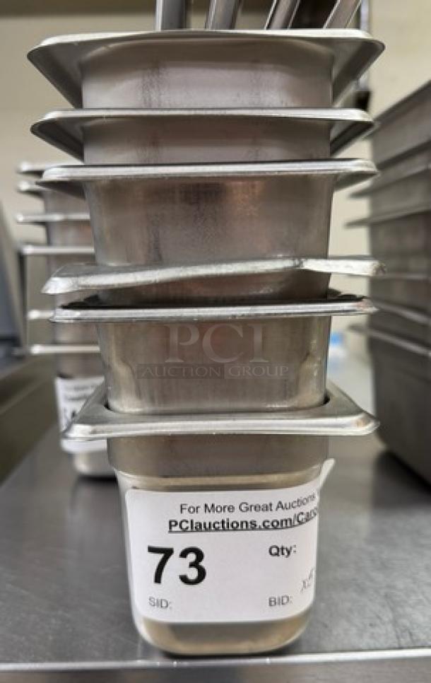 Stainless steel 1/6 x 4 pans with 3 lids, stackable, auction tag "73" visible, good condition, set of 6 for bid.