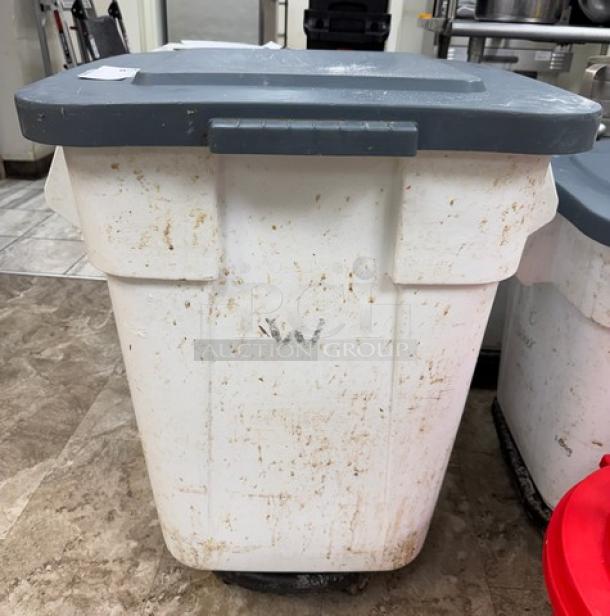 Rubbermaid 28 Gal. dry goods storage container on casters, grey lid, visible wear and dirt, ideal for bulk storage.