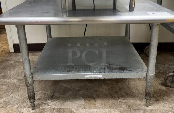 Stainless steel equipment stand with undershelf, used condition, visible wear and "Staff Drinks" label on the lower shelf.