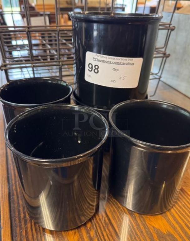 Six black round containers in good condition, labeled "Lot 98," displayed on a wooden surface.